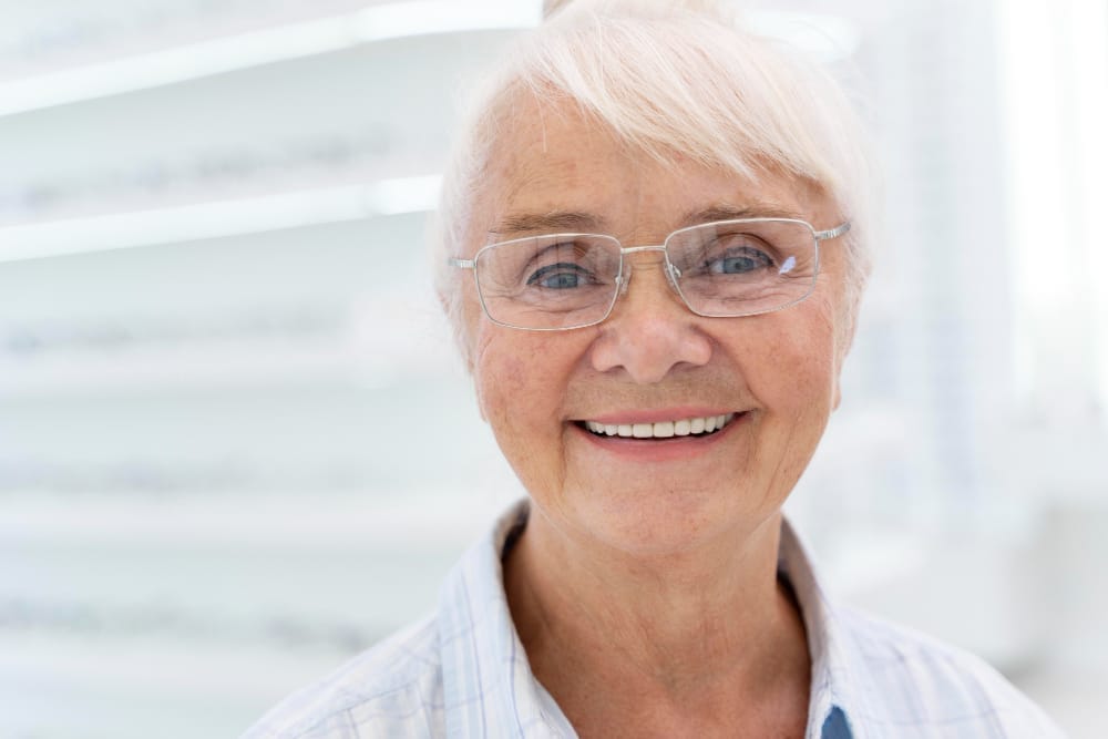 Elderly woman with glasses smiling.