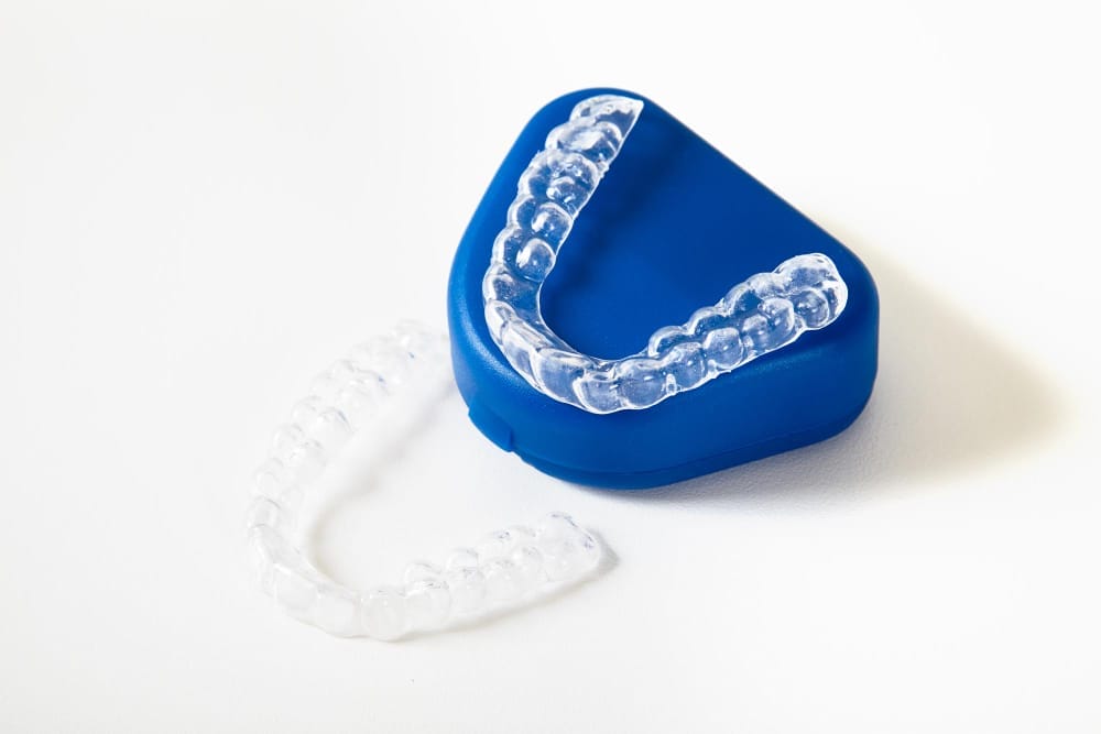 Clear dental aligners placed on and around a blue retainer case.